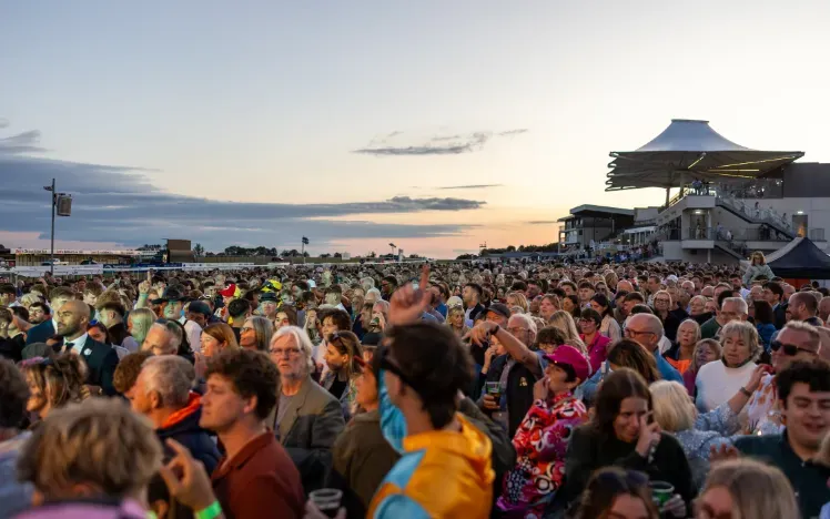 A large crowd at Bath Races enjoying live music in the sunset