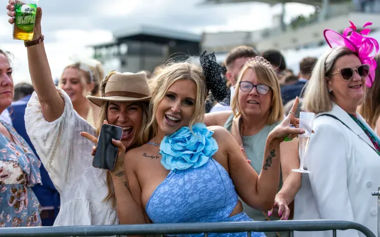 Two ladies at Bath Races pose in front of the crowd