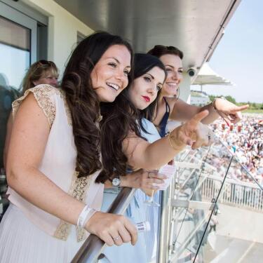 A group enjoying the view of afternoon racing from the hospitality balcony at Bath Racecourse.